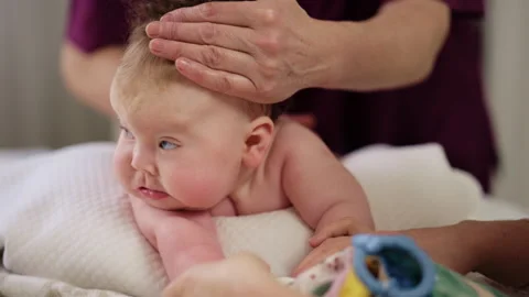 Baby lying on their tummy while an adult massages them and performs mobility 스톡 동영상 329401548