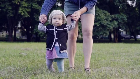A baby is making first steps with mother Stock Footage 77635047