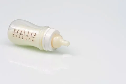 Baby milk bottle with reflection on a white background with copy space. Spill Stock Photos