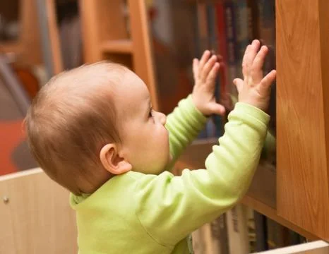 Baby near the bookcase Stock Photos