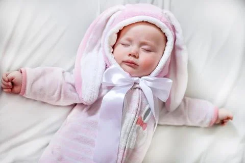 Baby newborn in a sleeping suit with the ears of an Easter bunny rests during a Stock-Fotos