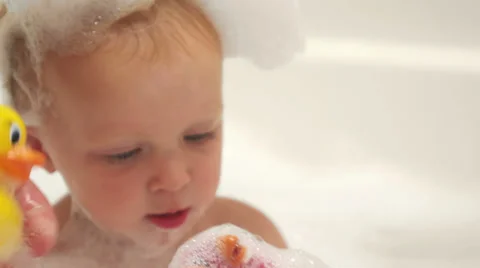 A baby is offered a rubber ducky while taking a bubble bath Vídeo Stock 33871514