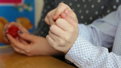 The baby opens the red ball. Pulls a gold ring out of the ball and puts it on hi Stock Footage 129813219