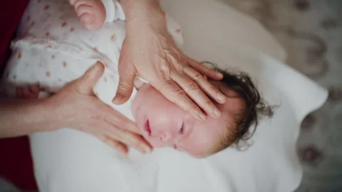 Baby placed on the back on a stability ball while adults support the infant's Stock Footage 329397289