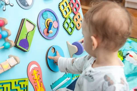 Baby playing with different entertaining elements on the game board Stock Photos