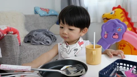 Baby playing kitchenware toy with fried egg in pan Stock Footage 99339922