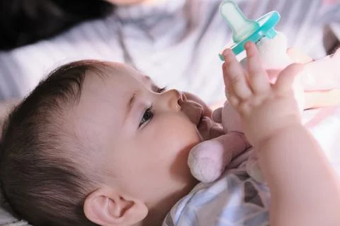 Baby playing with pacifier in bed 写真素材