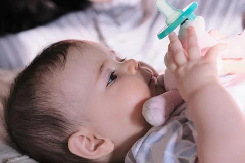 Baby playing with pacifier in bed 库存照片