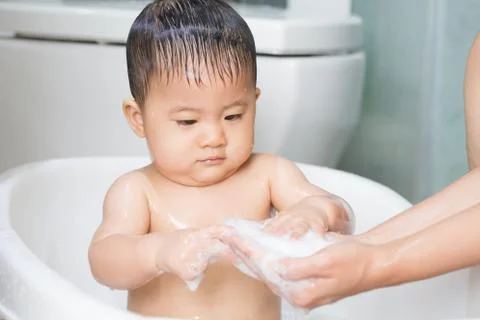 Baby playing soap bubbles during the bath Stock Photos