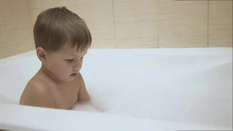 A baby plays with bubbles while taking a bath Stock Footage 77259636