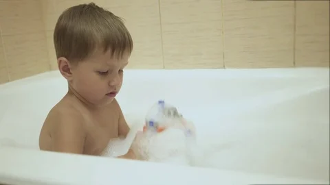 A baby plays with bubbles while taking a bath. 4K Stock Footage 77259929
