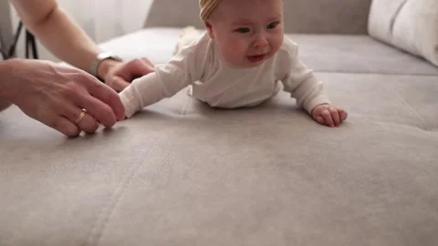 Baby practicing tummy time on a sofa with parental support and encouragement Stock Footage 340586846