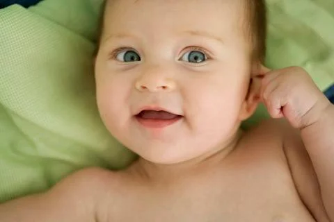 Baby pulling on ear, smiling Stock Photos