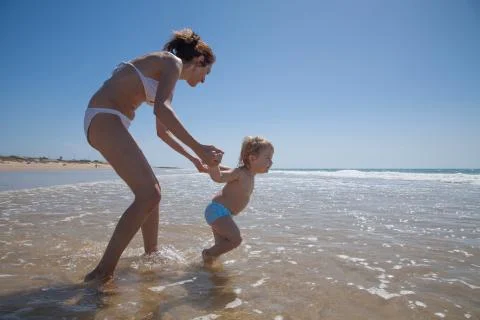 Baby pulling mom to ocean Stock-Fotos