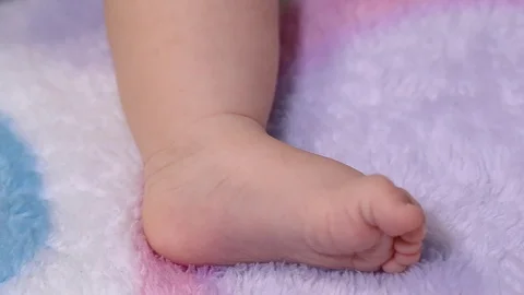 The baby pulls the foot, a very close-up Stock Footage 89296315