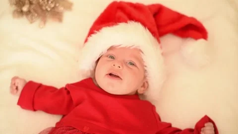 Baby in red Santa hat and red dress lies on white blanket. Stock Footage 219244368