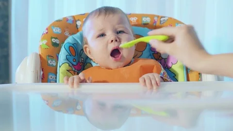 Baby reluctantly eats and winces in pleasure Stock Footage 72739984