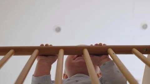 Baby rises to explore the sides of the crib in the nursery Stock Footage 341629627