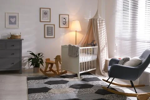 Baby room interior with comfortable crib and rocking chair Stock Photos