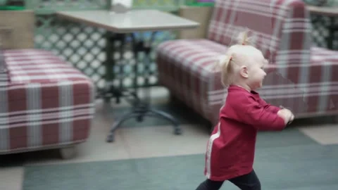 The baby runs between the empty couches in the pizzeria. 库存影片 144695098