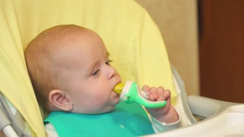The baby sits at the table and eats Stock Footage 141787152