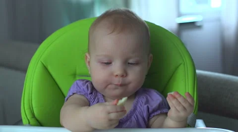 Baby sitting on chair and eats Vídeos de archivo 63986853