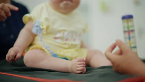 Baby sitting on examination table while pediatrician plays with a toy, ensuring Stock Footage 339810504