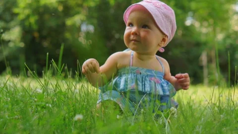 A baby is sitting on the grass Stock Footage 92157086