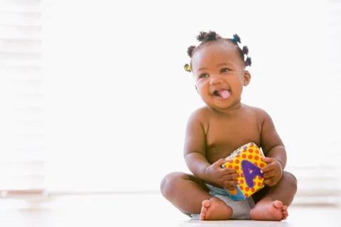Baby sitting indoors with block smiling Stock Photos