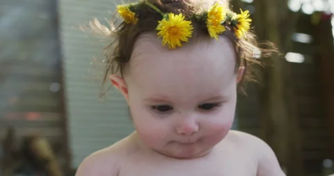 A baby sitting outside with looking off camera smiling. Stock Footage 132299865