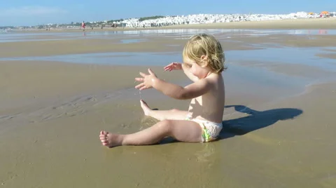 Baby sitting in puddle beach Stock Footage 58275852