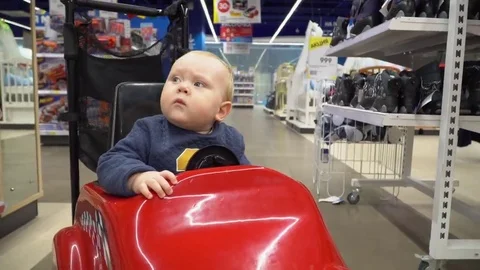 Baby sitting in the shopping cart in a store Stock Footage
