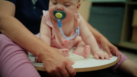 Baby sitting on a therapy disc, learning to balance, supported by an Stock Footage 339791171