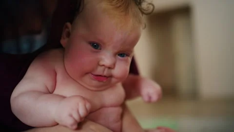 Baby sitting upright while being supported by an adult, showing effort and focus Stock Footage 329398289