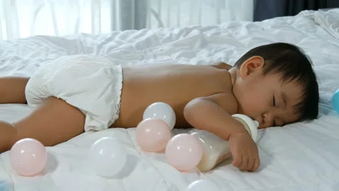 Baby sleeping on a bed after drinking bottle milk Stock-Footage 135511624