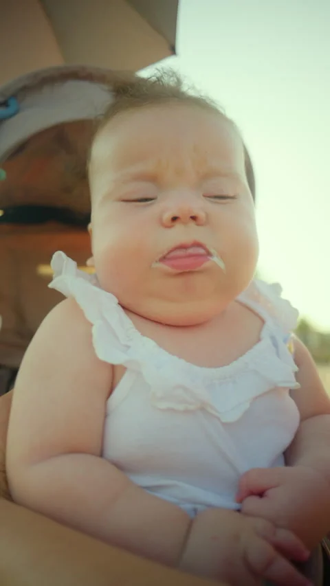 Baby sleeping peacefully in a stroller, small amount of milk on chin, enjoying a Stock Footage 343225269