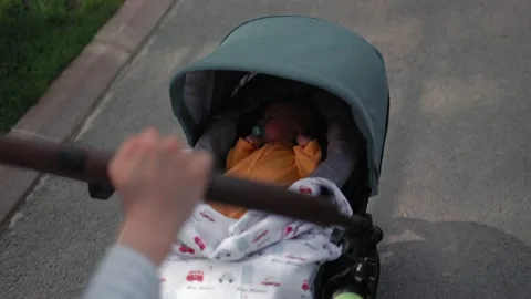 Baby sleeps in a stroller while walking in the park. Mom pushes a stroller Video stock 189350410
