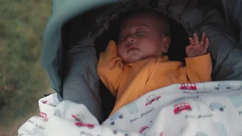 Baby sleeps in a stroller while walking in the park. Mom pushes a stroller Stock Footage 190884186