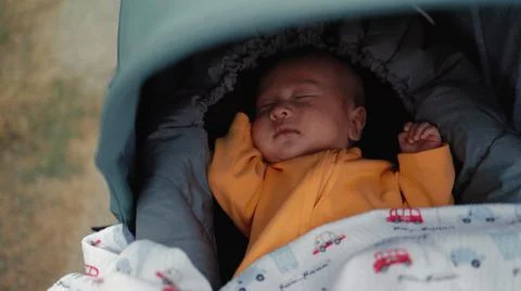 Baby sleeps in a stroller while walking in the park. Mom pushes a stroller Stock Photos