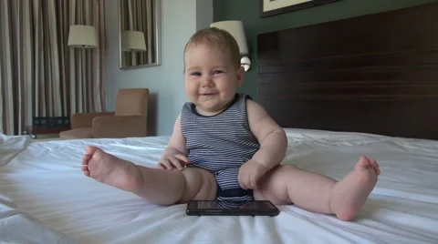 Baby with smartphone in bed Stock Footage 44122712