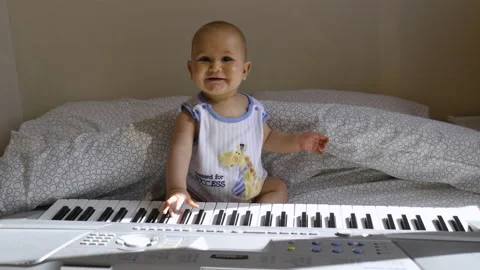 A baby smiles while playing the piano, in France Stock Footage 213730153