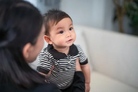 Baby smiling while being held by a caregiver in a bright indoor setting wit.. Stock Photos