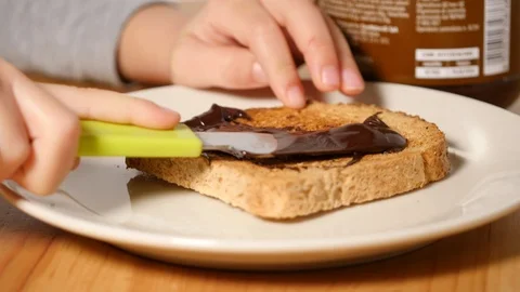 Baby is spreading chocolate on slice of bread. greedy food, healthy greedy food. Video stock 100303631