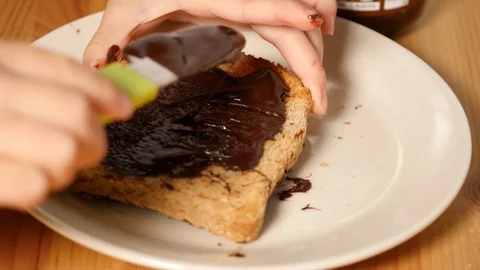 Baby is spreading chocolate on slice of bread. greedy food, healthy greedy food. Stock Footage 100303657