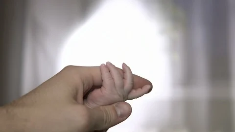 The baby squeezes a tiny hand on his father's finger. Stock Footage 87924799
