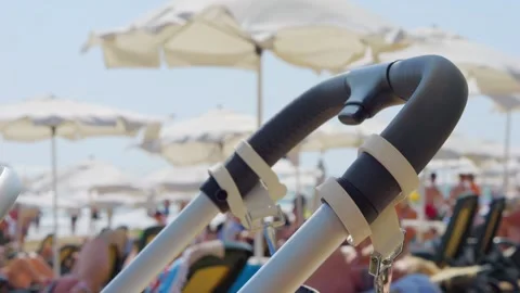 Baby stroller on beach with umbrellas in the background in 4k slow motion 1.. Stock Footage 283255448