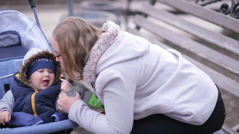 A baby in a stroller eats cookies and laughs while looking at mom Stock Footage 116771483