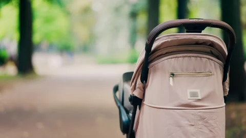 Baby stroller parked on path in summer park with bokeh background motion. Stock Footage 339425943
