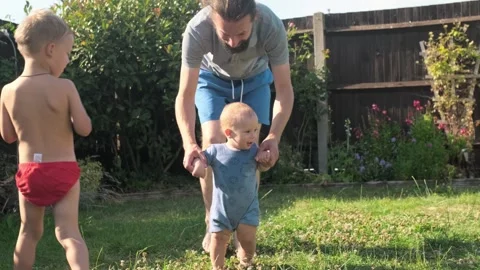 Baby takes first steps in grass. Dady Father walks with son in nature kid dream Stock Footage 247550106