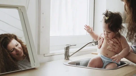 Baby taking bath in kitchen sink child playing Stock Footage 79795762